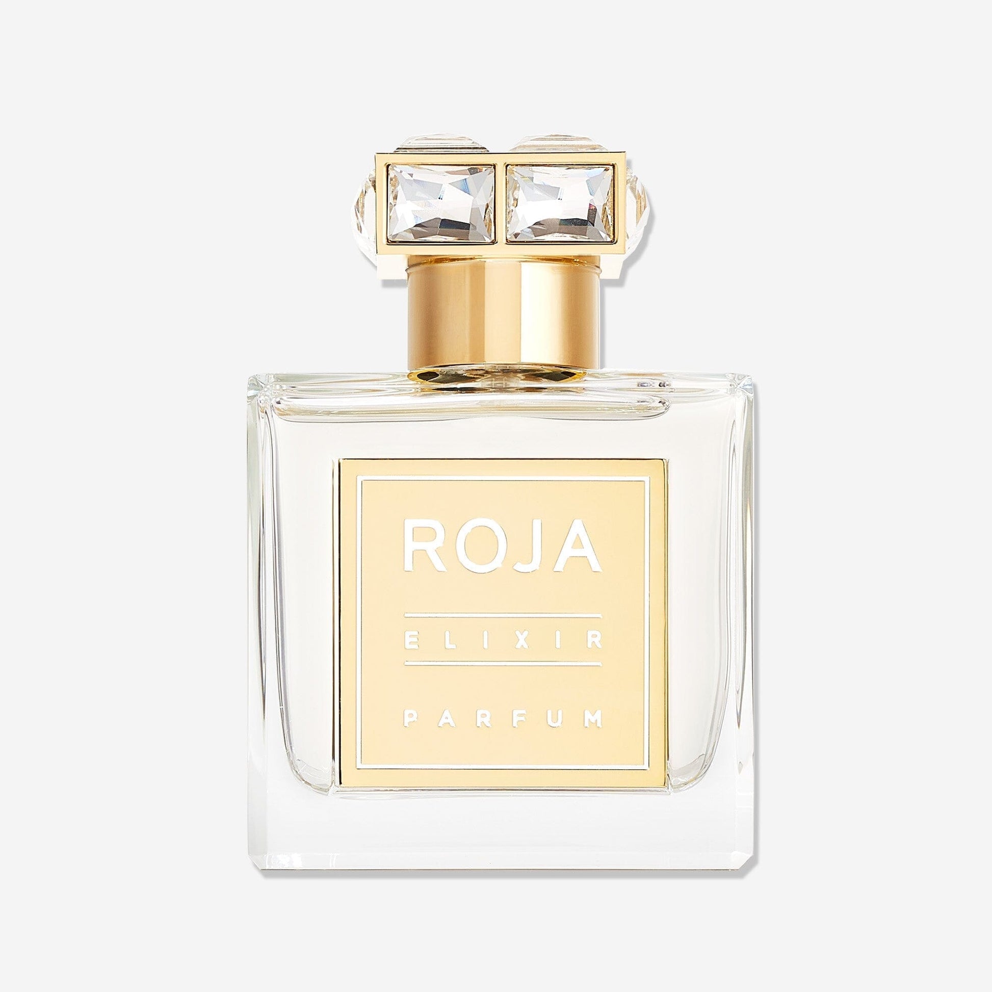 A clear glass bottle of Roja Parfums Elixir Pour Femme with a gold label and cap topped by two large square crystals, set against a white backgroundâ€”an ethereal fragrance featuring vanilla, amber, and musk inside.