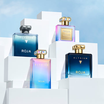 Three bottles of Roja Elysium 168极速赛车官方开奖结果记录体彩-极-168飞艇历史记录查询结果体彩网-极速赛车168官网记录体彩查询网 , each with a geometric cap, are displayed on white, stepped blocks against a blue sky. The bottles have blue and iridescent gradients with gold and silver accents.