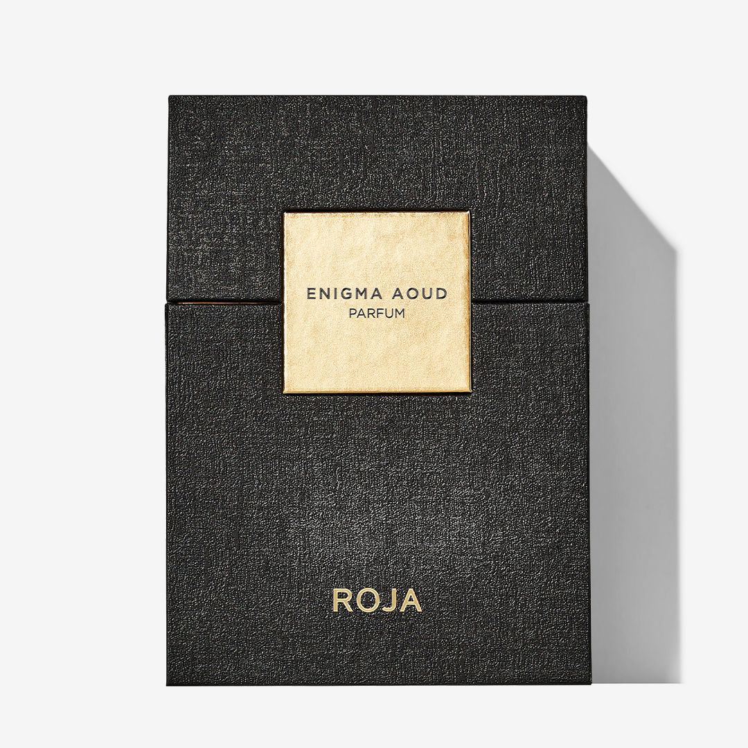 A black textured box with a gold label reading Enigma Aoud Parfum at the center and Roja at the bottom—an elegant packaging by Roja Parfums, perfect for fans of luxurious Aoud fragrances.