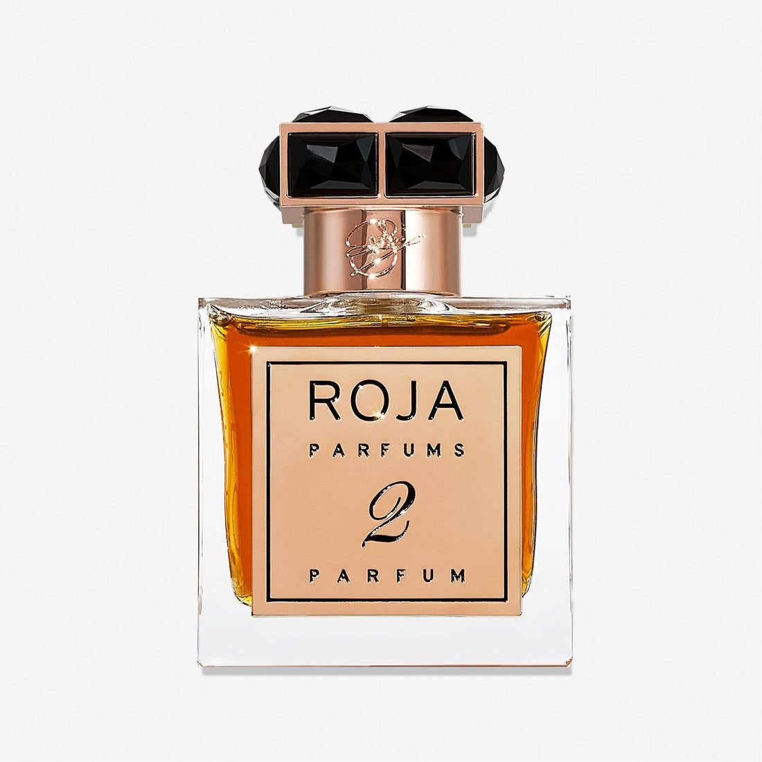 A rectangular glass bottle of Roja Parfums Parfum De La Nuit 2 features amber liquid, a gold label, and a black and gold faceted capâ€”an elegant choice for lovers of seductive scent, shown against a plain white background.