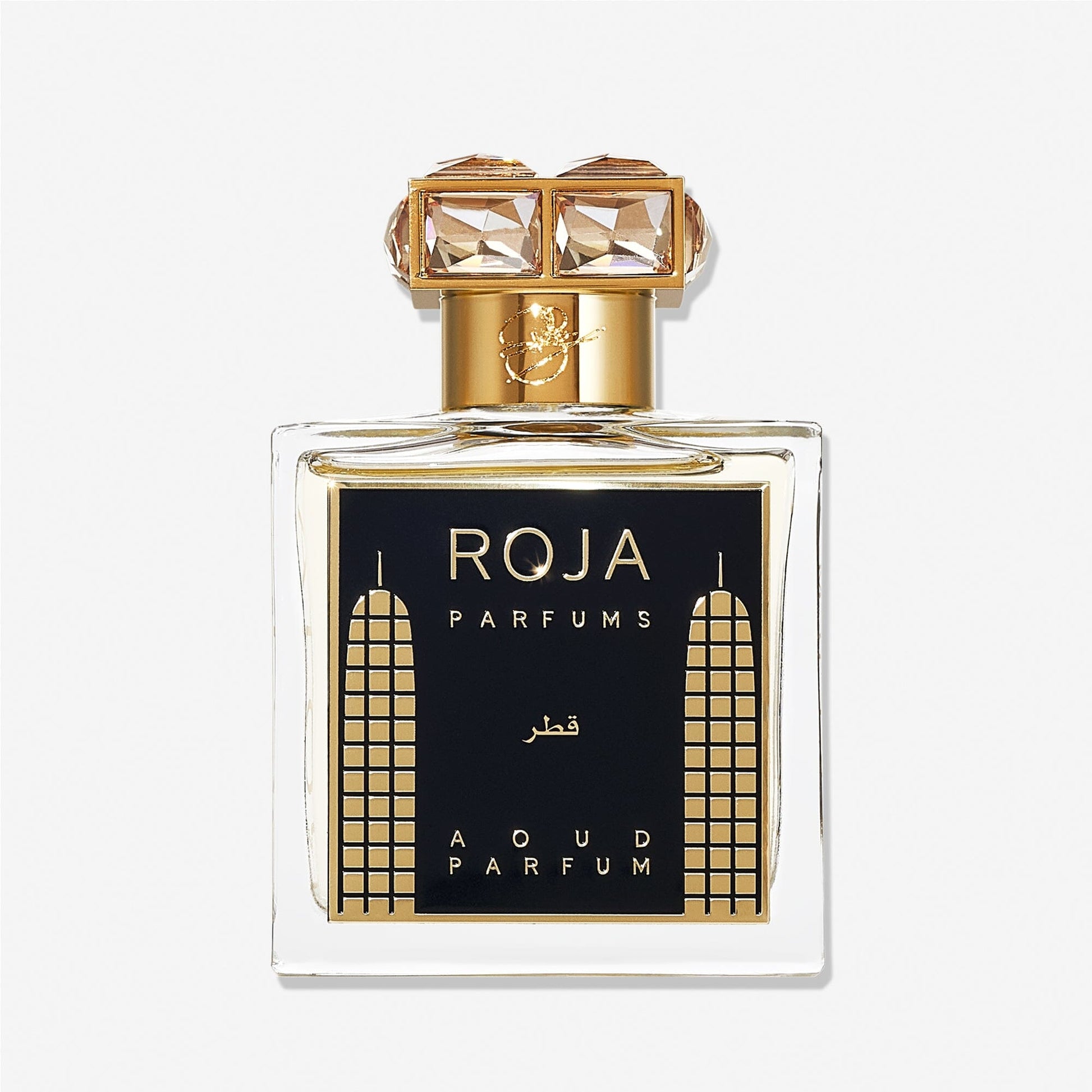 A luxury Roja Parfums Qatar perfume bottle features gold accents, geometric designs, and a crystal-studded gold capâ€”evoking notes of peach and pear in its lavish presentation.