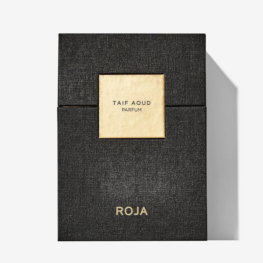 A black textured Taif Aoud box from Roja Parfums features a gold square label with the product and brand name, evoking Arabian Rose notes, and casts a shadow on a white background.